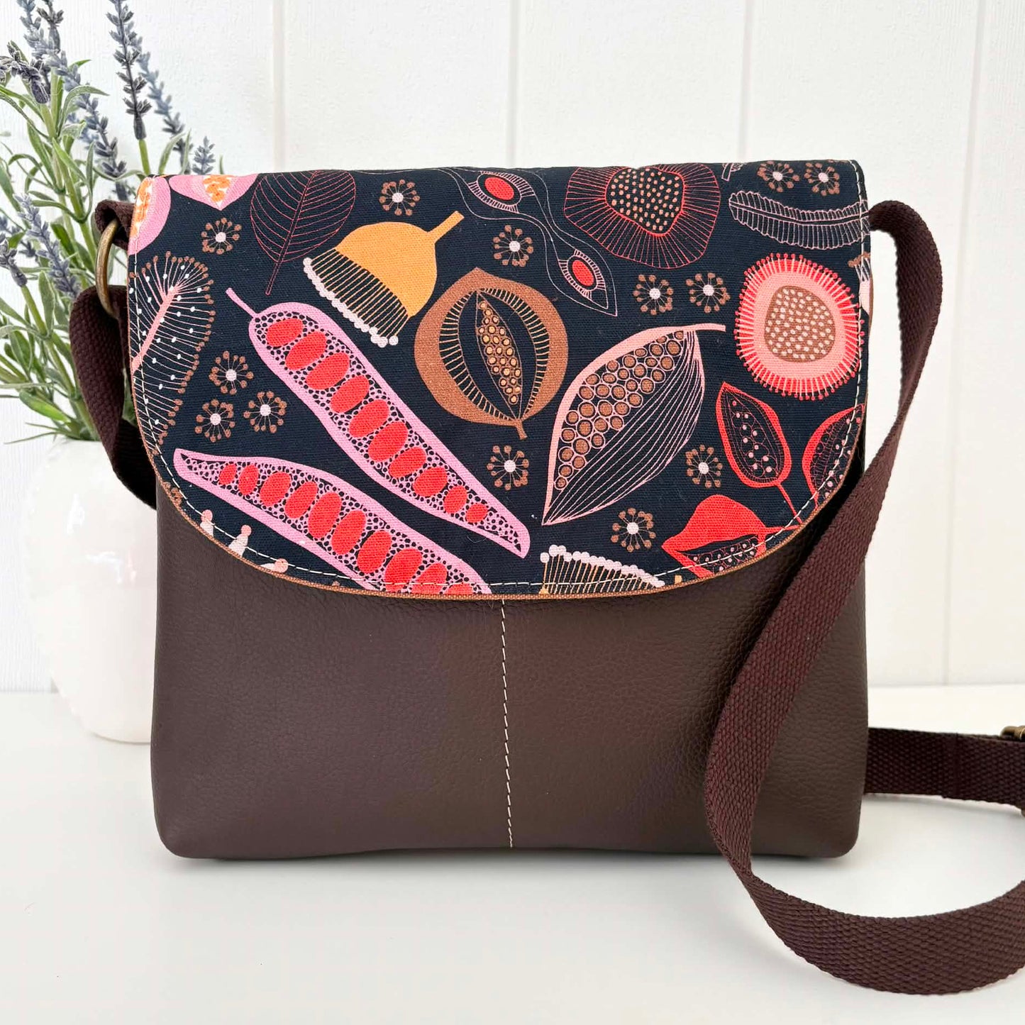 Brown crossbody bag with floral pattern on a white surface