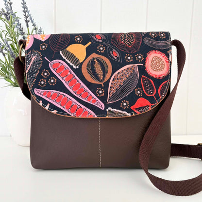 Brown crossbody bag with floral pattern on a white surface