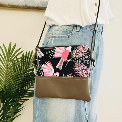 Crossbody bag with floral design on a person wearing a white shirt and blue jeans.