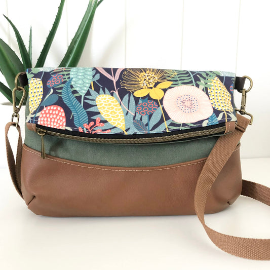 Multicolored floral-patterned bag with brown leather accents on a white background