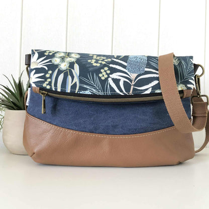 Floral-patterned bag with a brown strap on a white surface